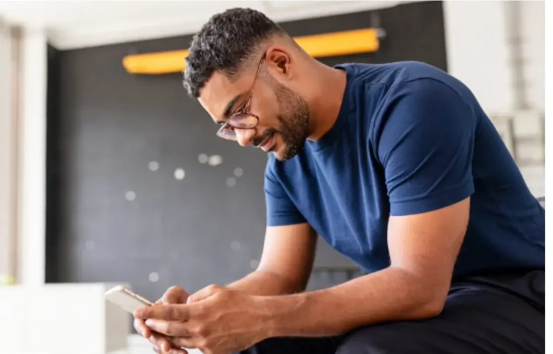 A man in a blue shirt looking at a cell phone