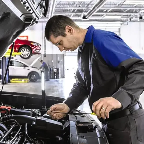 Technician servicing vehicle under the hood