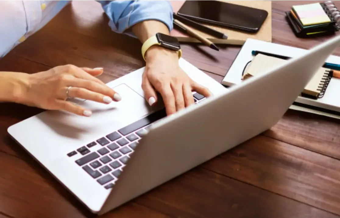 A woman's hands typing on a laptop