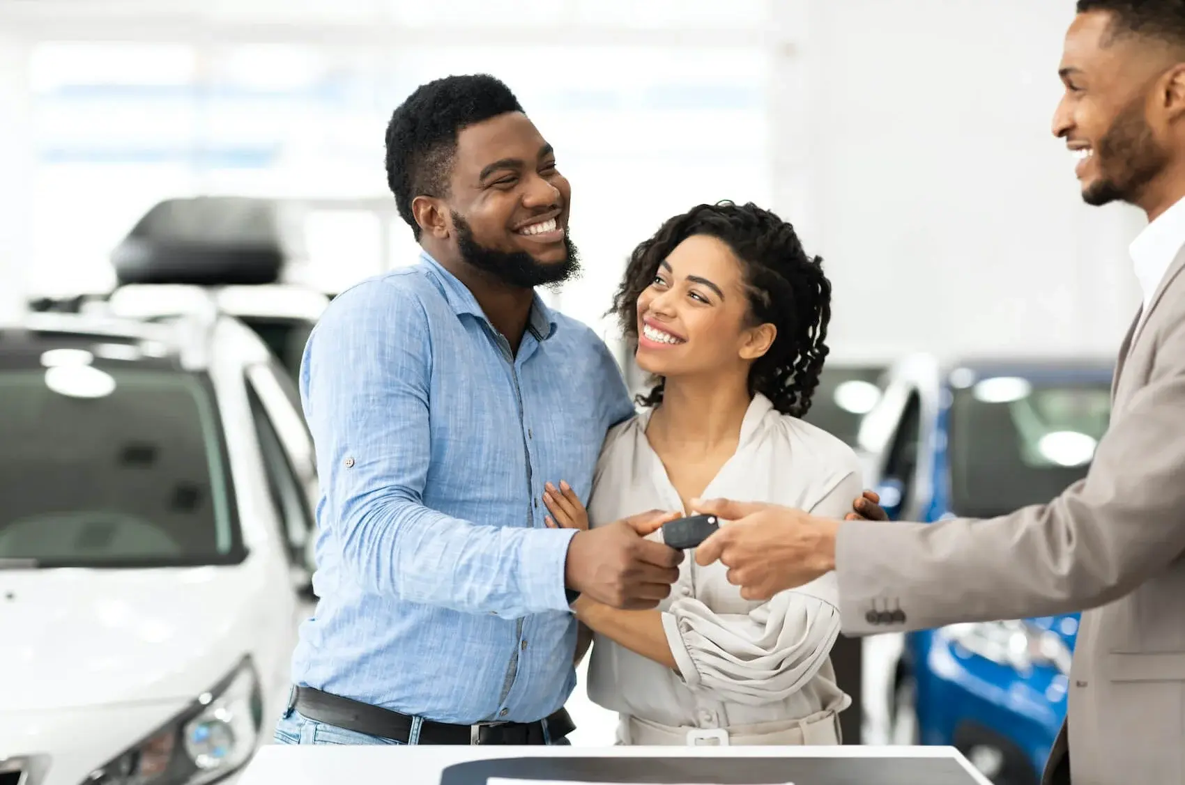 Sales consultant handing keys to customer in dealer showroom