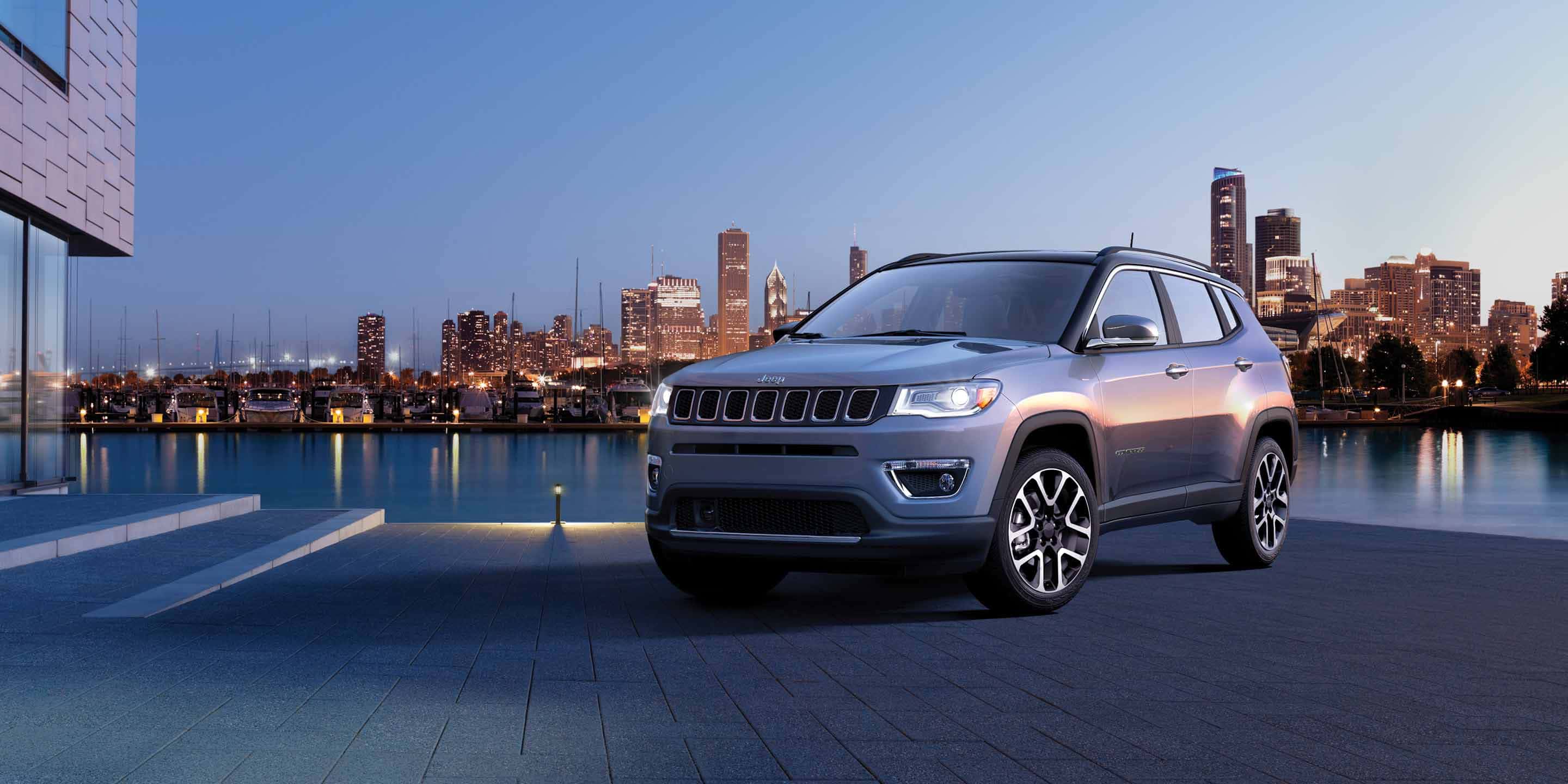 2019 Jeep Compass exterior shot with gray paint color parked on a stone road near brick buildings