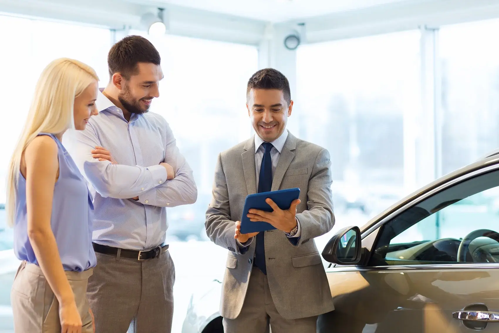 Sales manager talking to a couple in the dealership showroom