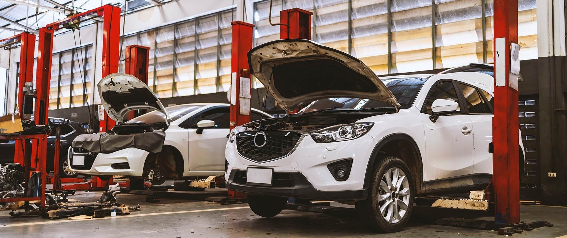 A row of white cars ready for repairs in a service center.