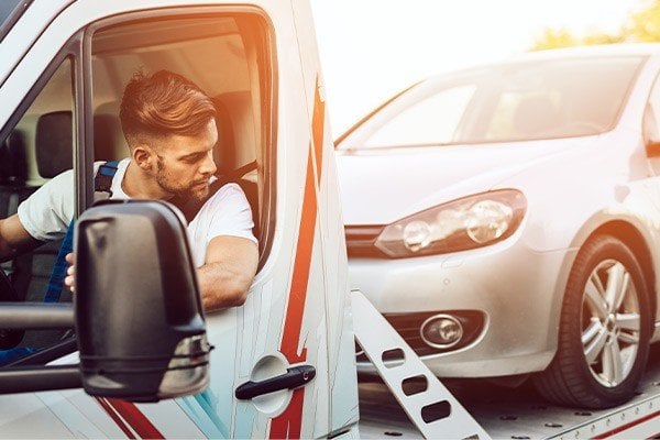 Man delivering vehicle on tow truck