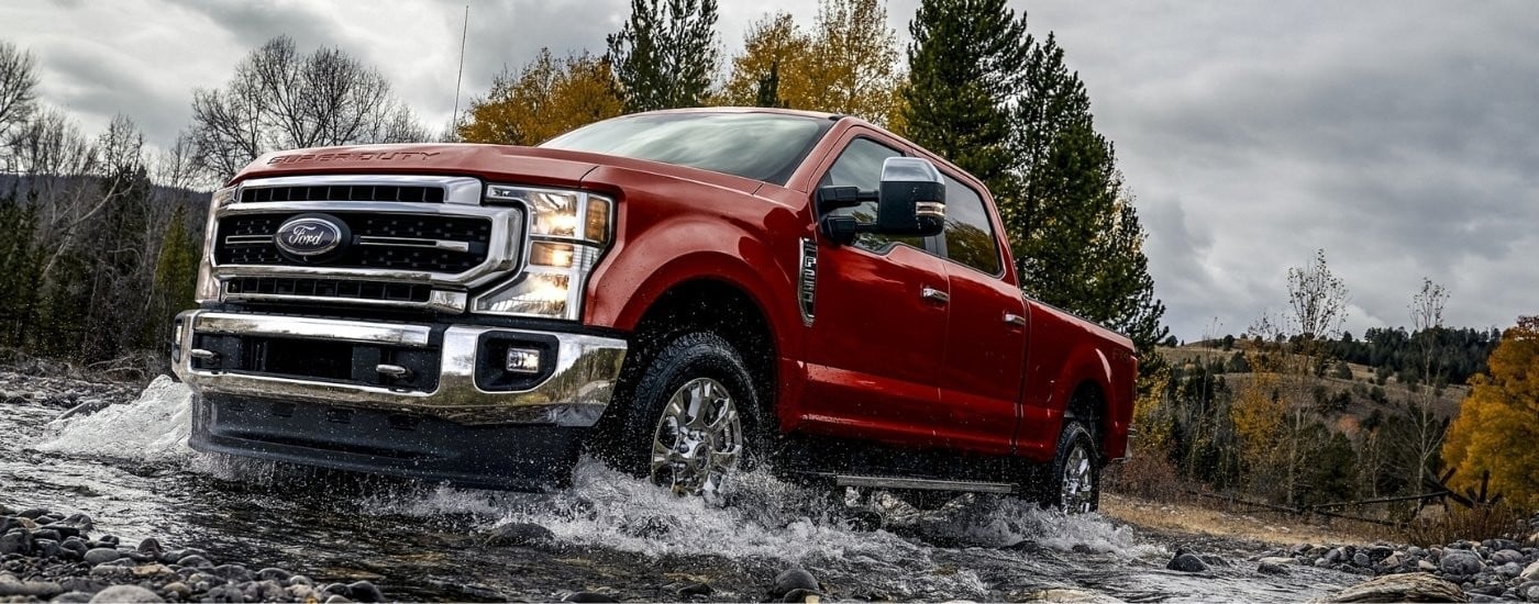 Red 2020 Ford F-250 driving through a creek
